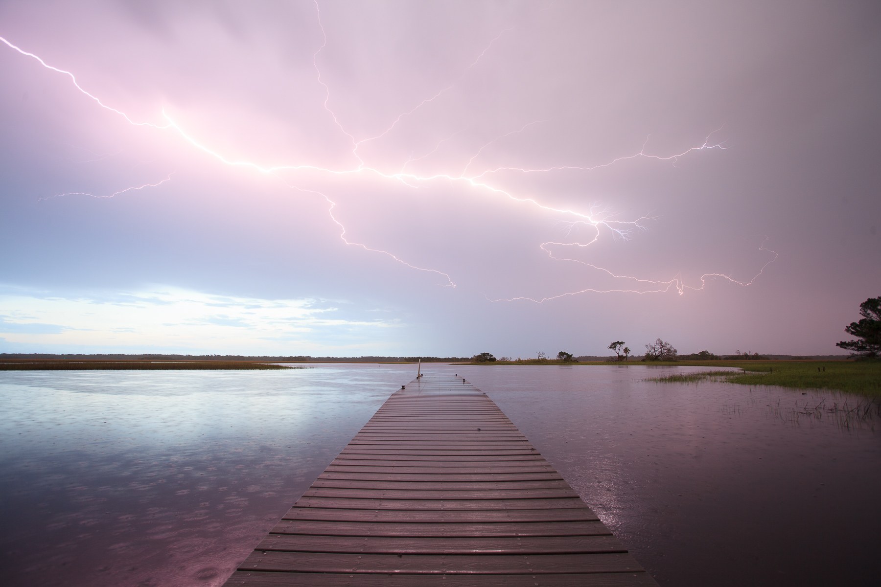 Unedited photograph of lightning striking over a dock in a saltwater marsh in Northeast Florida