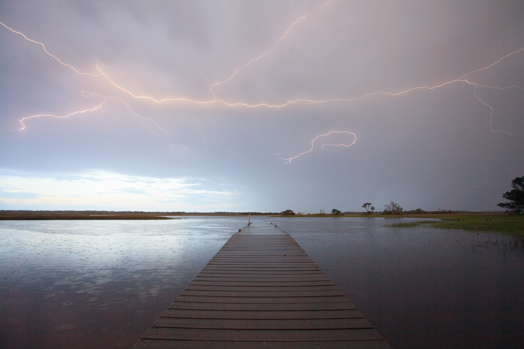 Unedited photograph of lightning striking over a dock in a saltwater marsh in Northeast Florida