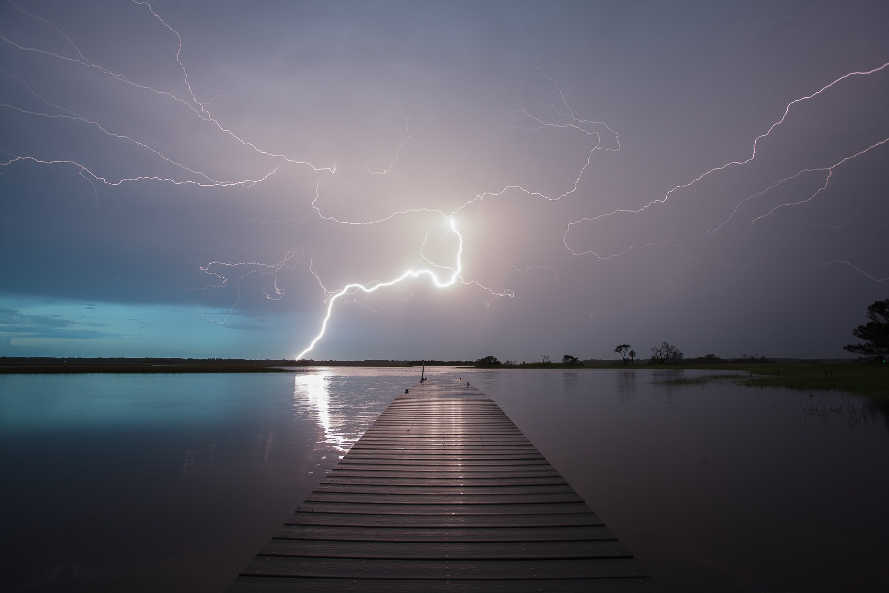 Unedited photograph of lightning striking over a dock in a saltwater marsh in Northeast Florida