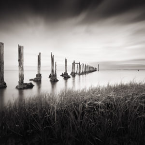 A black and white image of a dilapidated dock on the shore of the Gulf of Mexico