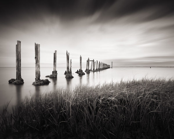 A black and white image of a dilapidated dock on the shore of the Gulf of Mexico